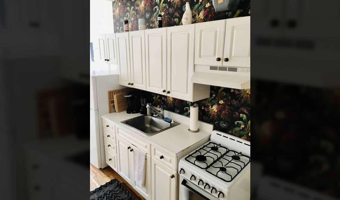 bright white kitchen cabinet with printed wallpaper