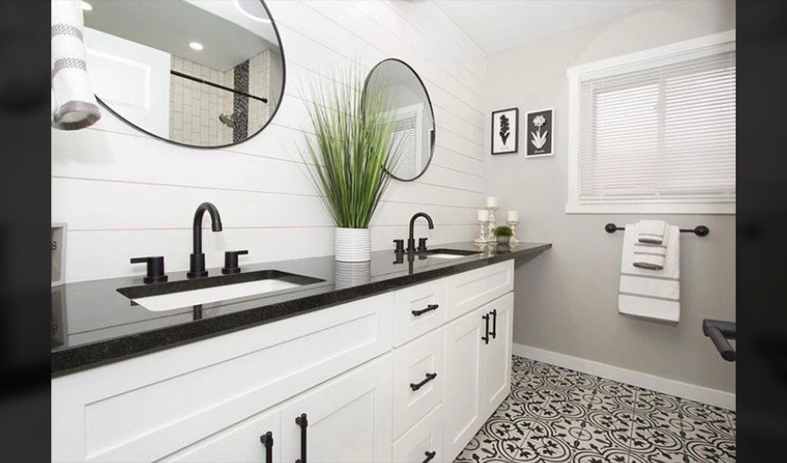 White bathroom vanities with black counter top and round mirror